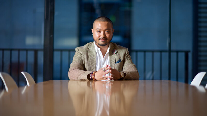 A man in a jacket seated at a boardroom table