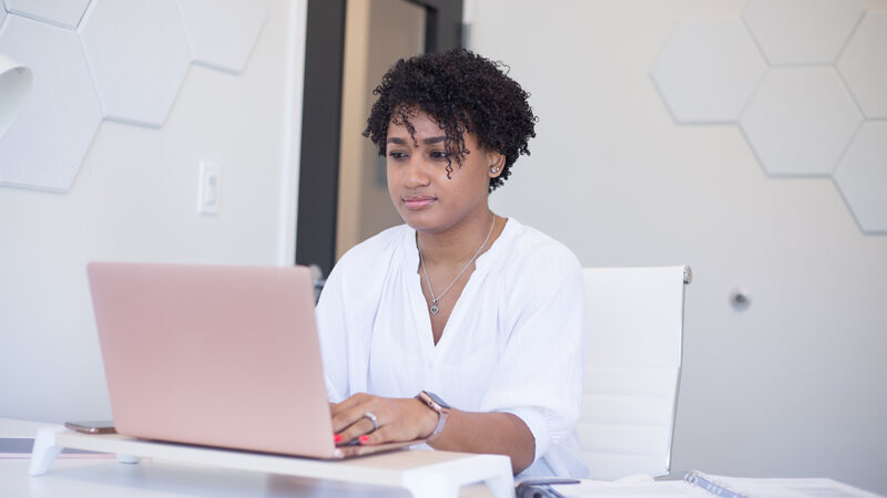 A woman working at a laptop in a bright office