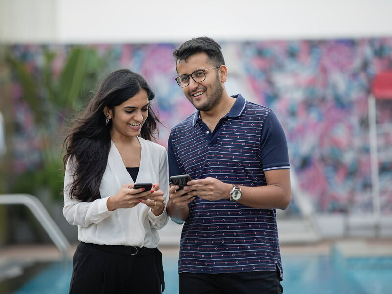 Two colleagues comparing notes on their phones outside